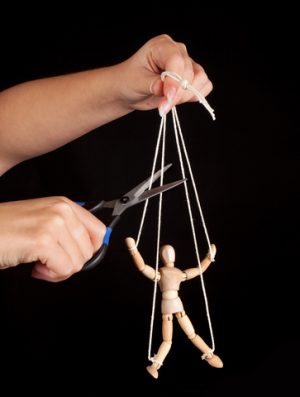 Hand cutting the strings of a puppet, giving it freedom